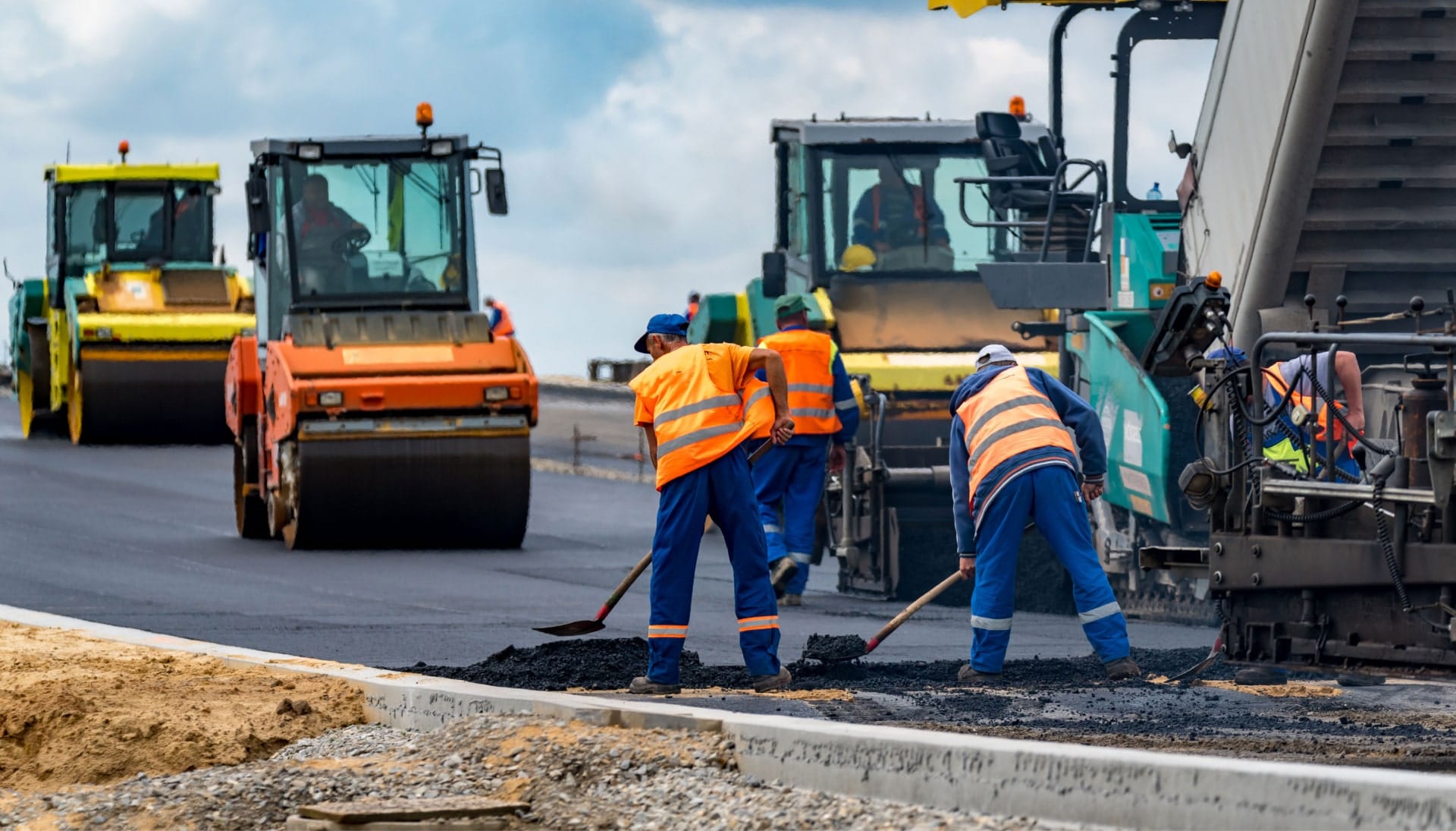 A group of construction workers wearing hard hats and reflective vests, operating heavy machinery and laying down asphalt on a newly excavated road in Saint Petersburg, showcasing the intricate process of building a sturdy and smooth surface.
